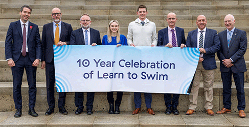 Representatives of the partnership holding a sign which says 10 year Celebration of Learn to Swim