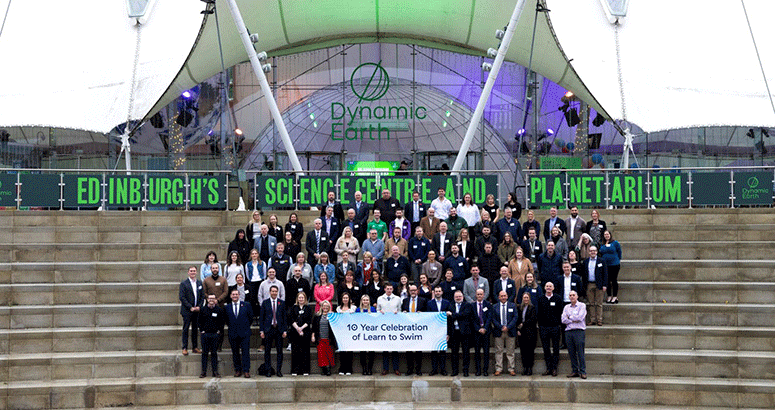 Large group on steps of Edinburgh's Dynamic Earth building, to celebrate 10 years of Learn to Swim programme